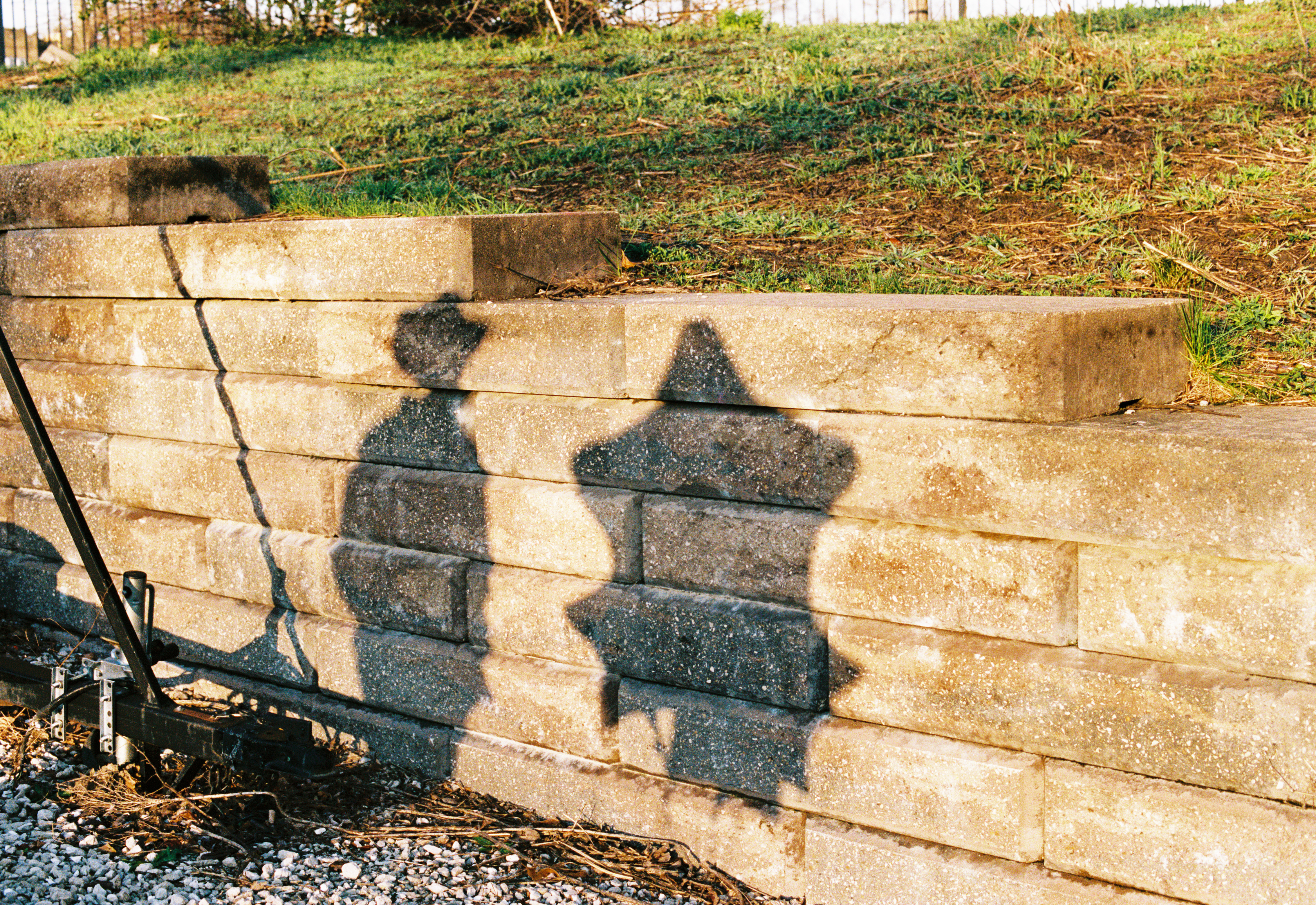 Concrete wall with shadows of a person in a cowboy hat and a bunch of star-shaped balloons
